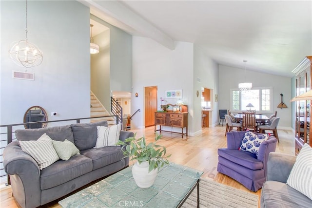 living area with visible vents, stairs, baseboards, light wood finished floors, and a notable chandelier