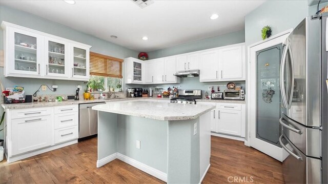 kitchen with under cabinet range hood, stainless steel appliances, white cabinets, and dark wood finished floors