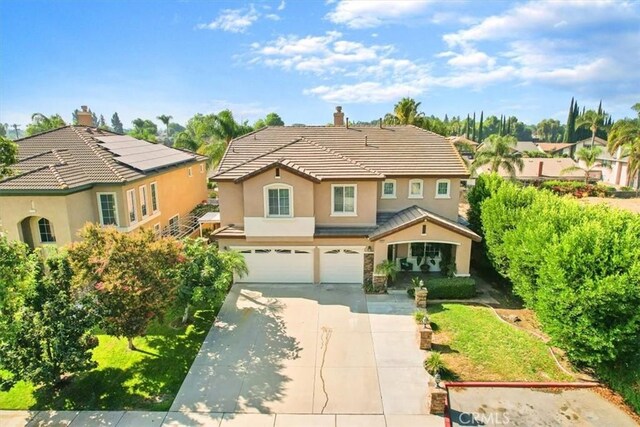 view of front of property featuring stucco siding, a chimney, a tiled roof, concrete driveway, and an attached garage