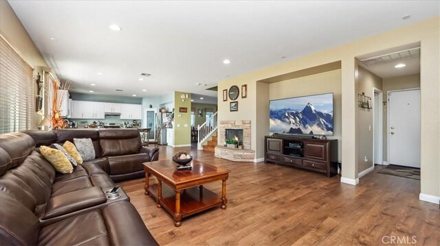living room featuring light wood finished floors, a fireplace, recessed lighting, baseboards, and visible vents