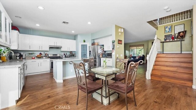 dining room with visible vents, stairs, wood finished floors, baseboards, and recessed lighting