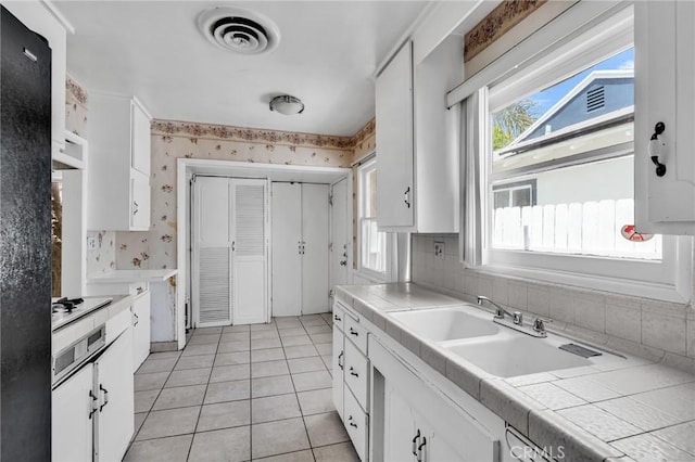 7038 Mclennan Ave, Lake Balboa, CA 91406 - kitchen featuring tile counters, white cabinets, wallpapered walls, and visible vents