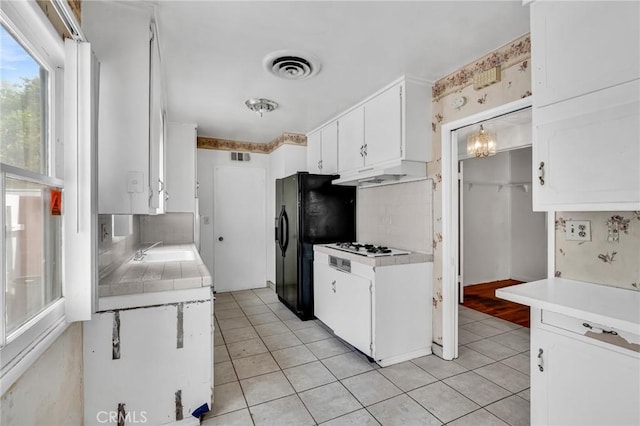 7038 Mclennan Ave, Lake Balboa, CA 91406 - kitchen with light tile patterned floors, a sink, black refrigerator with ice dispenser, under cabinet range hood, and white cabinetry
