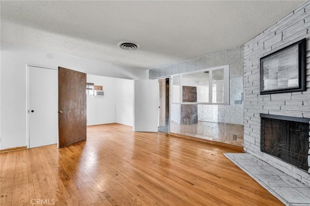 7038 Mclennan Ave, Lake Balboa, CA 91406 - unfurnished living room featuring a brick fireplace, a textured ceiling, visible vents, and wood finished floors