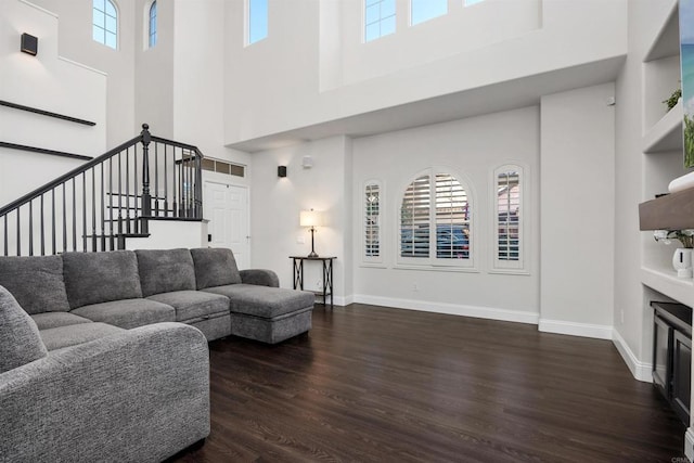 living room featuring plenty of natural light, wood finished floors, and a towering ceiling