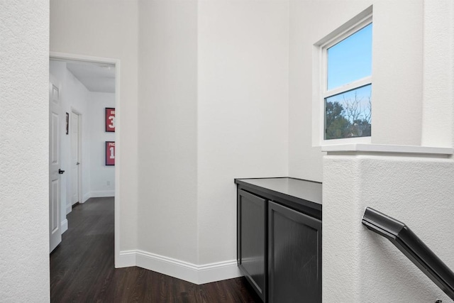 hall with dark wood-type flooring and baseboards