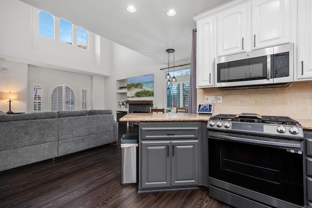 kitchen with a peninsula, open floor plan, gray cabinets, white cabinetry, and appliances with stainless steel finishes