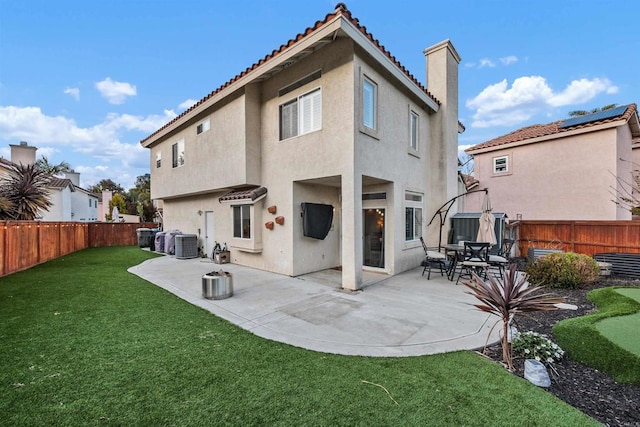 back of property featuring a lawn, a tiled roof, a fenced backyard, and stucco siding