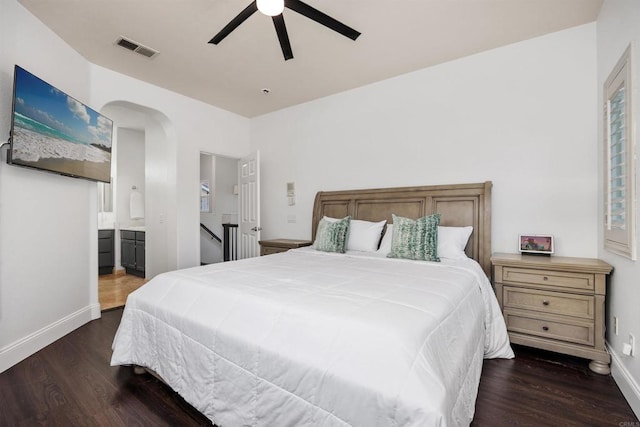 bedroom with visible vents, arched walkways, dark wood-style flooring, and baseboards
