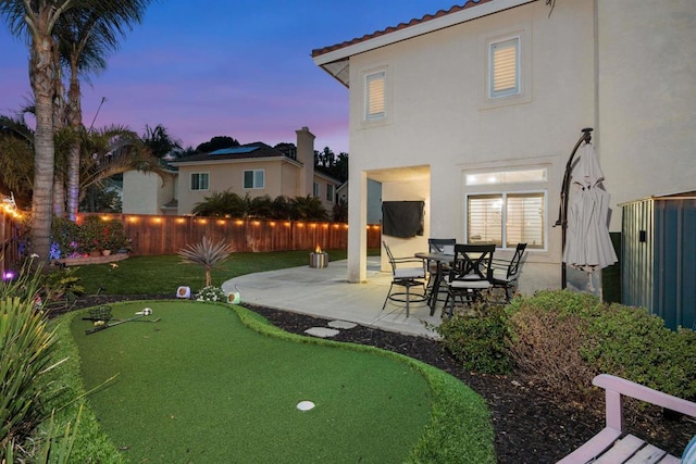 yard at dusk featuring a patio and a fenced backyard