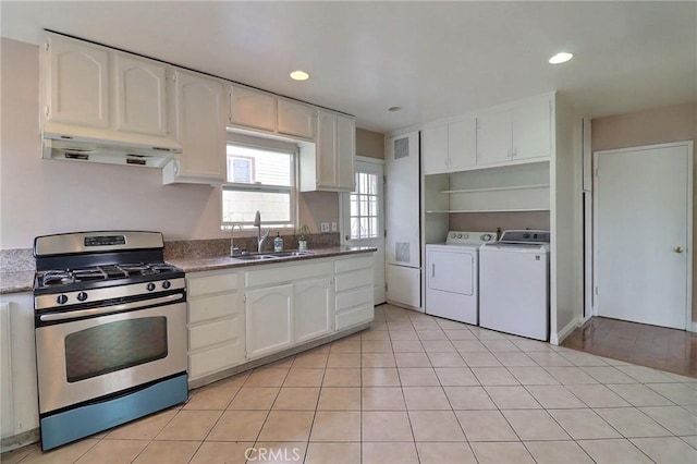 kitchen featuring stainless steel gas range, washing machine and clothes dryer, a sink, white cabinetry, and under cabinet range hood