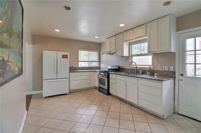 kitchen with a sink, stainless steel gas range, freestanding refrigerator, and a wealth of natural light