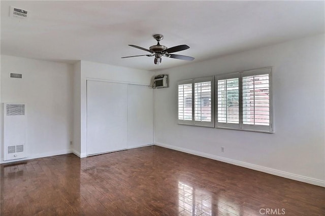 unfurnished room with ceiling fan, a wall mounted air conditioner, baseboards, visible vents, and hardwood / wood-style flooring