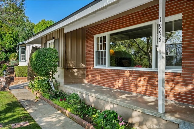 view of property exterior featuring board and batten siding, a porch, and brick siding