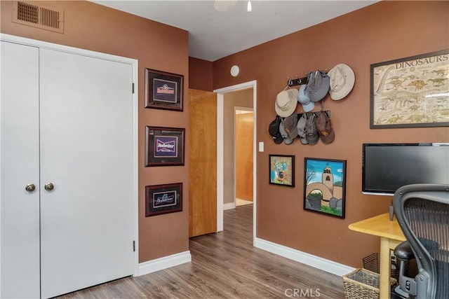 office featuring baseboards, visible vents, and wood finished floors