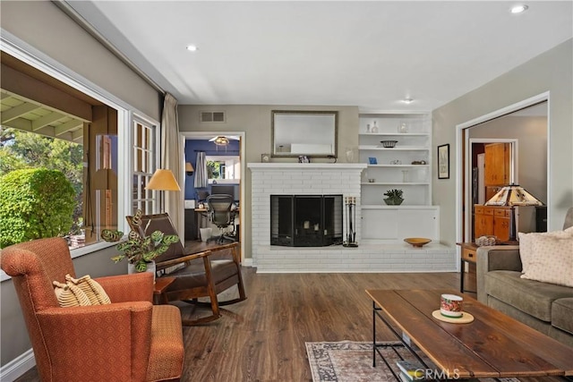 living area featuring visible vents, recessed lighting, dark wood-style flooring, and a fireplace
