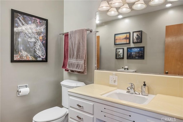 bathroom featuring vanity, backsplash, and toilet