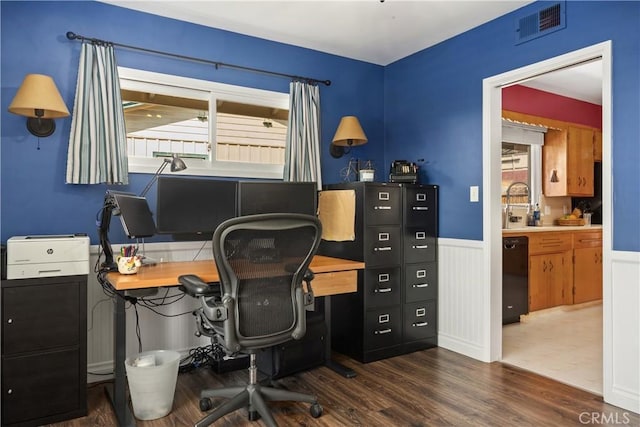 office space featuring a sink, a wainscoted wall, dark wood-type flooring, and visible vents