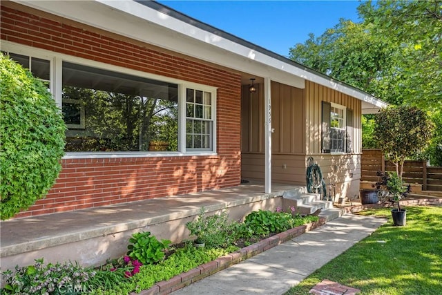 entrance to property with covered porch, brick siding, and board and batten siding