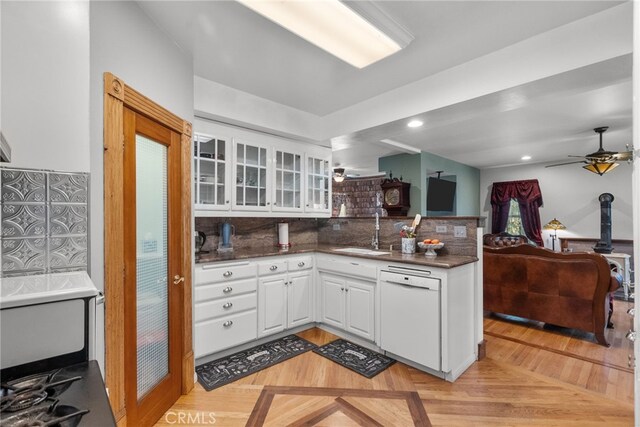 kitchen featuring white cabinets, a peninsula, a sink, and dishwasher