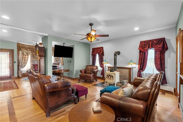 living room with plenty of natural light, a wood stove, a ceiling fan, and recessed lighting