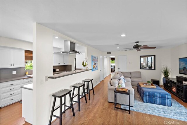 living room with recessed lighting, ceiling fan, light wood-type flooring, and a wealth of natural light