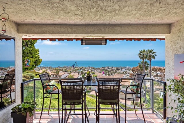 balcony featuring a water view and outdoor dining area