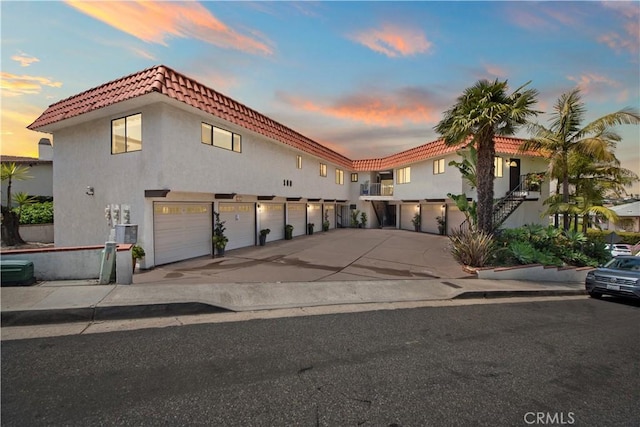 view of front of property featuring stucco siding, driveway, a tile roof, and cooling unit