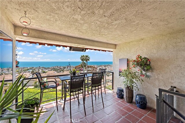 balcony with a water view and outdoor dining space