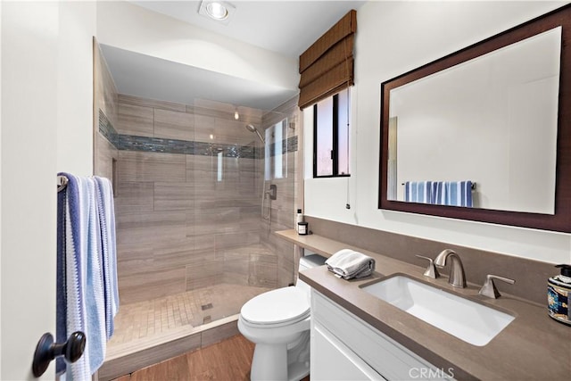 bathroom featuring vanity, a tile shower, and toilet