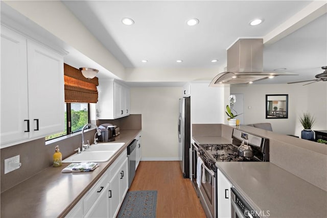 kitchen with white cabinets, appliances with stainless steel finishes, a sink, light wood-style floors, and island exhaust hood