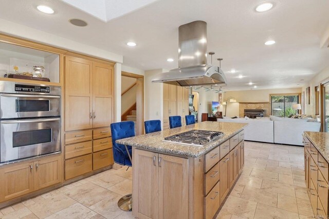 kitchen featuring a kitchen island, island range hood, recessed lighting, light stone counters, and appliances with stainless steel finishes