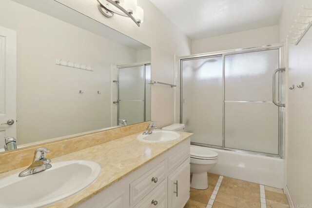 full bath featuring a sink, tile patterned floors, toilet, and double vanity