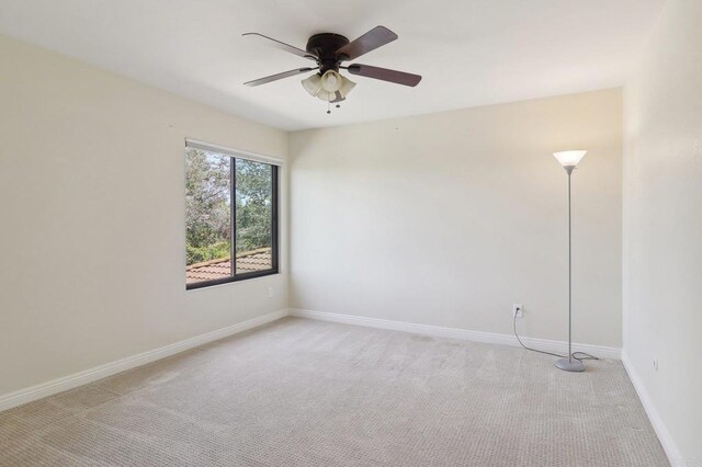 empty room featuring baseboards, light carpet, and a ceiling fan