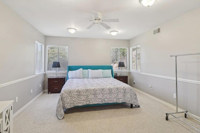 carpeted bedroom featuring baseboards, ceiling fan, and visible vents