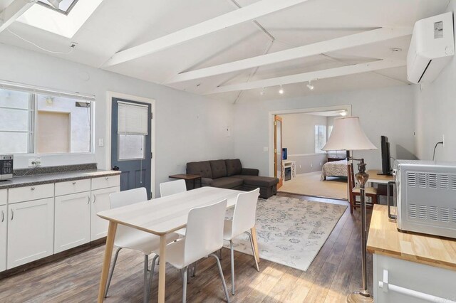 dining area with a wall unit AC, wood finished floors, and lofted ceiling with skylight