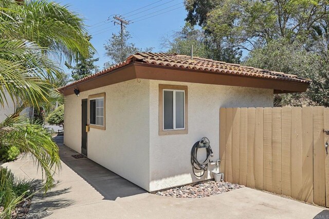 view of side of home featuring a tile roof and stucco siding