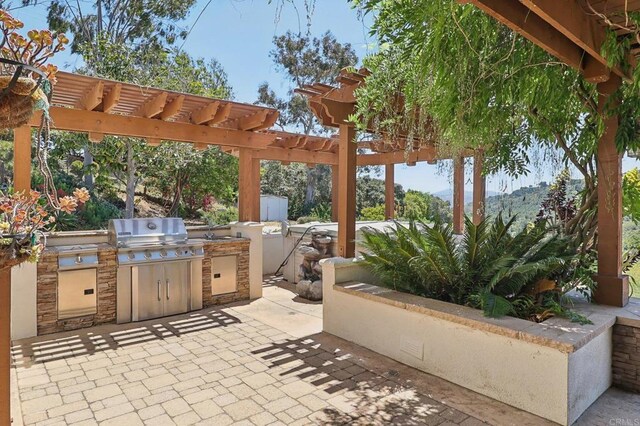 view of patio / terrace featuring grilling area, exterior kitchen, and a pergola