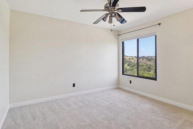 unfurnished room with baseboards, ceiling fan, and light colored carpet