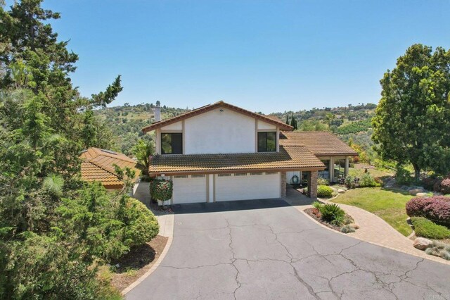 view of front facade with a garage, aphalt driveway, stucco siding, and a tiled roof