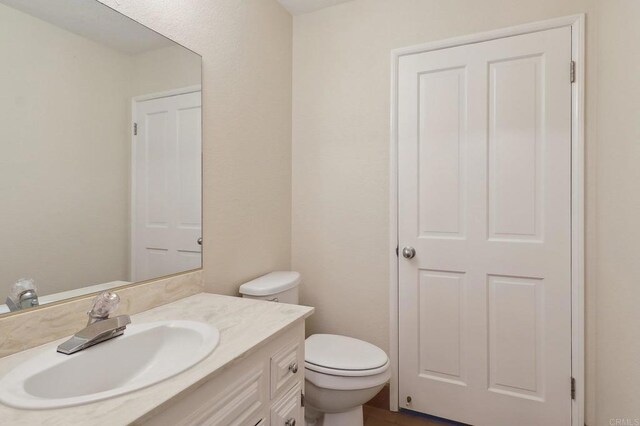 half bathroom featuring vanity and toilet