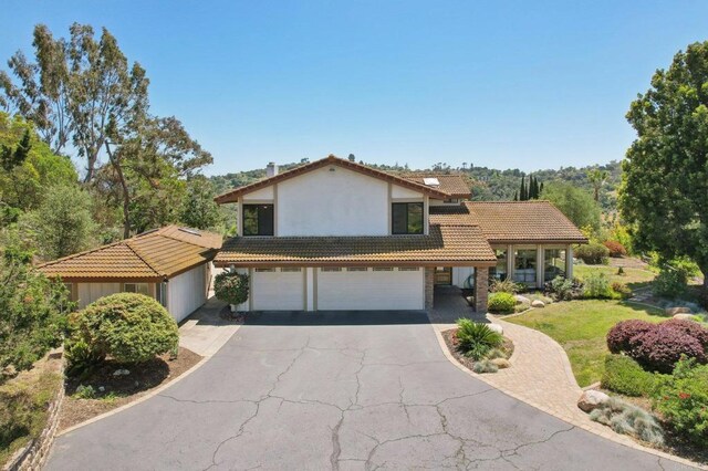 view of front of home featuring aphalt driveway, a garage, stucco siding, a front yard, and a tiled roof