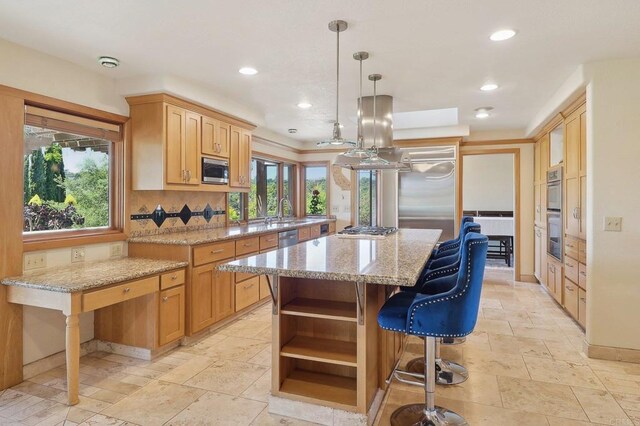 kitchen with plenty of natural light, a kitchen island, open shelves, stone tile flooring, and built in appliances