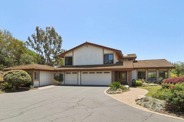 traditional-style house with an attached garage, aphalt driveway, and a tiled roof