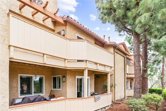 back of house featuring a balcony and stucco siding