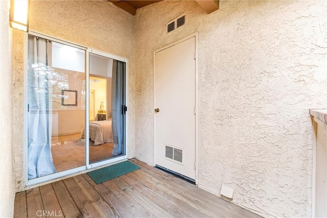 entrance to property featuring visible vents and stucco siding