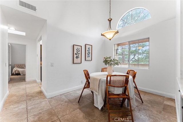 dining room with baseboards, a wealth of natural light, stone tile floors, and visible vents