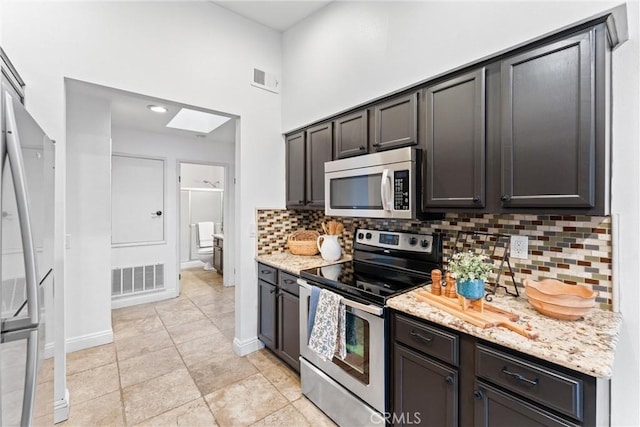 kitchen featuring a skylight, appliances with stainless steel finishes, visible vents, and tasteful backsplash