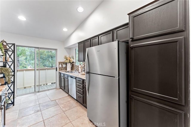 kitchen with dark brown cabinetry, appliances with stainless steel finishes, a sink, recessed lighting, and lofted ceiling