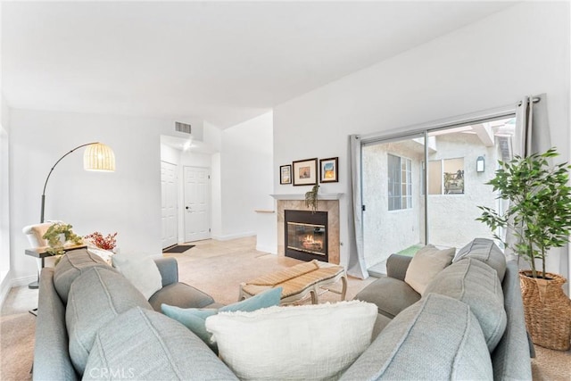 living area with a tiled fireplace, baseboards, light carpet, and visible vents